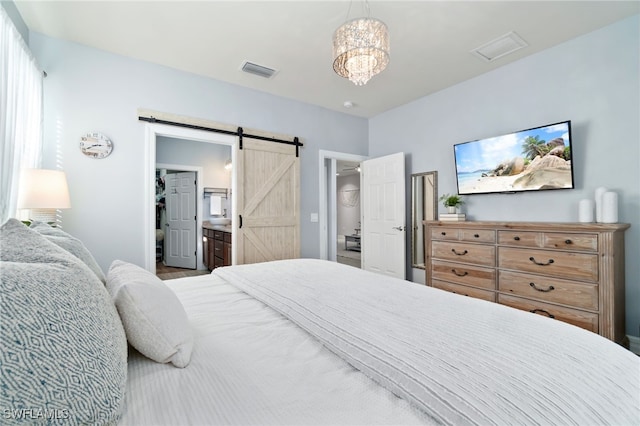 bedroom with a barn door, ensuite bath, and a notable chandelier