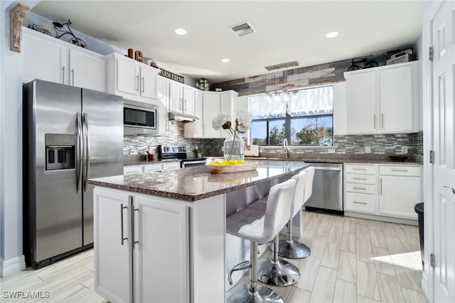 kitchen with a center island, white cabinetry, appliances with stainless steel finishes, and tasteful backsplash