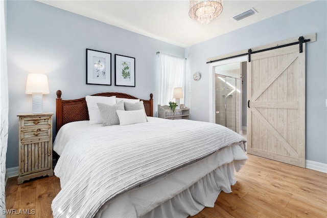 bedroom featuring a barn door and light hardwood / wood-style flooring