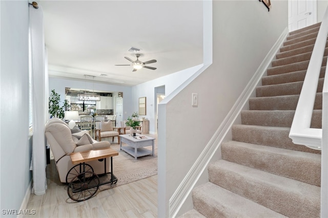 stairway with ceiling fan and wood-type flooring