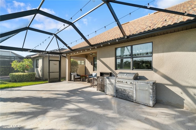 view of patio / terrace featuring a lanai, area for grilling, ceiling fan, and exterior kitchen