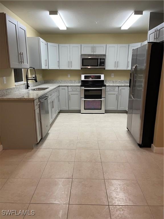 kitchen with gray cabinets, sink, light tile patterned floors, and stainless steel appliances