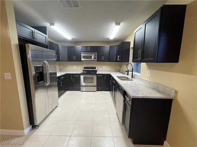 kitchen featuring light tile patterned flooring, light stone countertops, sink, and appliances with stainless steel finishes