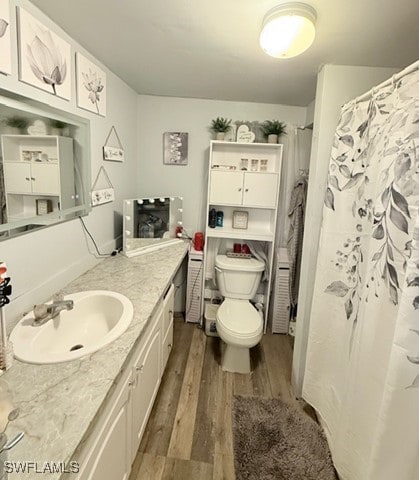 bathroom featuring hardwood / wood-style flooring, vanity, curtained shower, and toilet