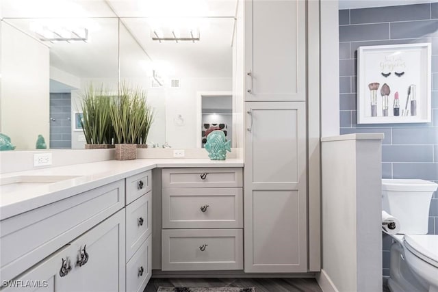 bathroom with vanity, toilet, wood-type flooring, and tile walls