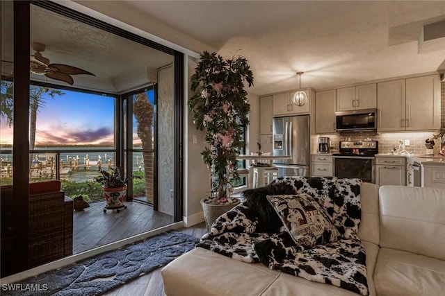 living room featuring ceiling fan, a water view, a wall of windows, and light hardwood / wood-style flooring