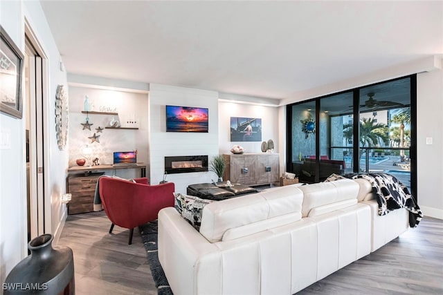 living room with floor to ceiling windows, a large fireplace, and hardwood / wood-style flooring