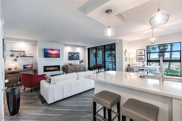 kitchen with floor to ceiling windows, white cabinetry, dark hardwood / wood-style flooring, decorative light fixtures, and a breakfast bar area