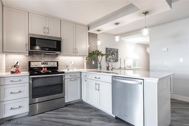 kitchen featuring kitchen peninsula, stainless steel appliances, hanging light fixtures, and sink