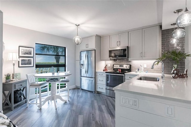 kitchen with white cabinetry, sink, stainless steel appliances, dark wood-type flooring, and pendant lighting