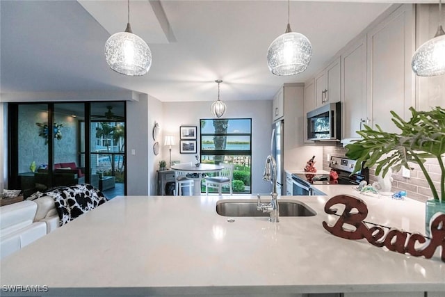 kitchen with hanging light fixtures, sink, white cabinets, and stainless steel appliances