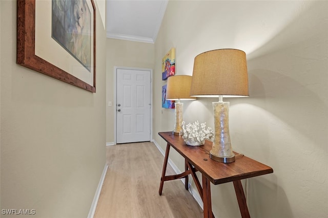 hallway with light hardwood / wood-style floors, vaulted ceiling, and ornamental molding