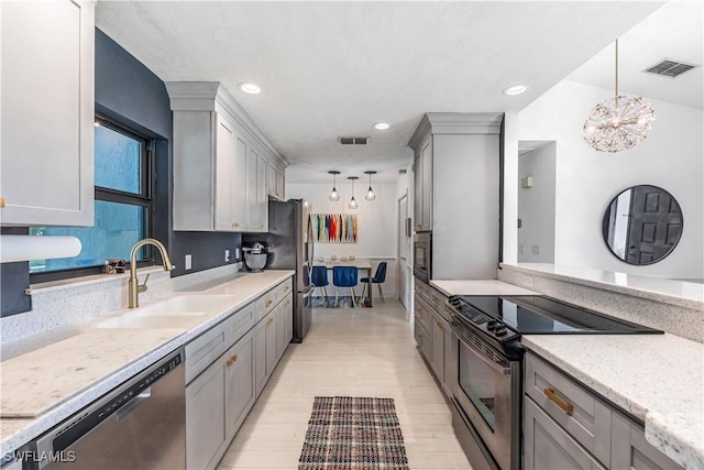 kitchen featuring pendant lighting, gray cabinetry, sink, light wood-type flooring, and appliances with stainless steel finishes