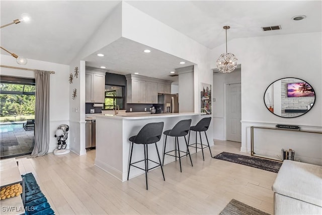 kitchen with stainless steel fridge, decorative light fixtures, lofted ceiling, and an inviting chandelier