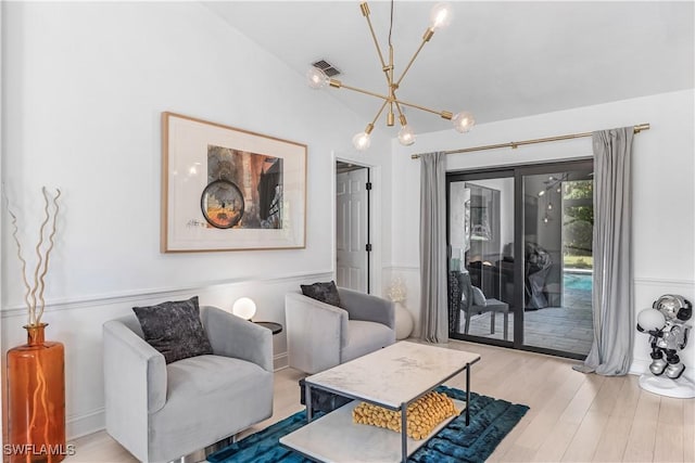 living room with light hardwood / wood-style flooring, vaulted ceiling, and a notable chandelier