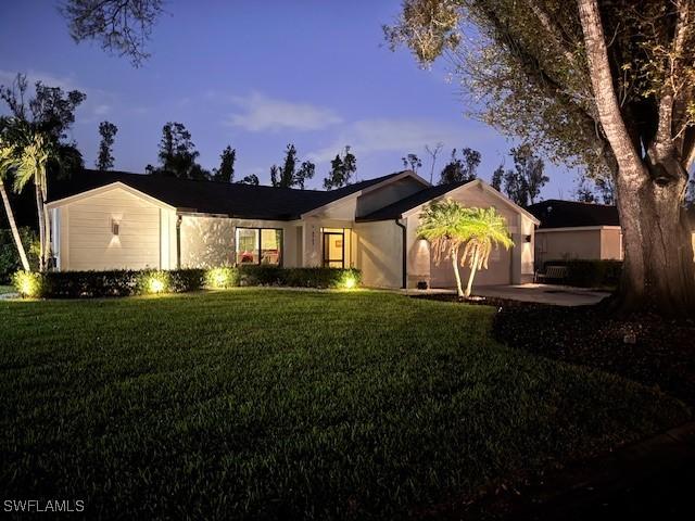 ranch-style home featuring a lawn and a garage