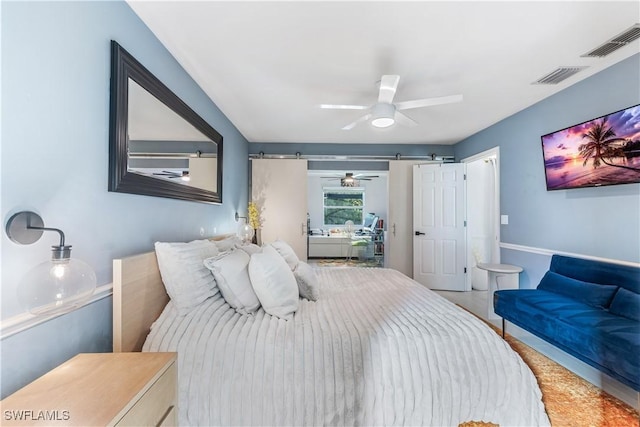 bedroom with ceiling fan and a barn door