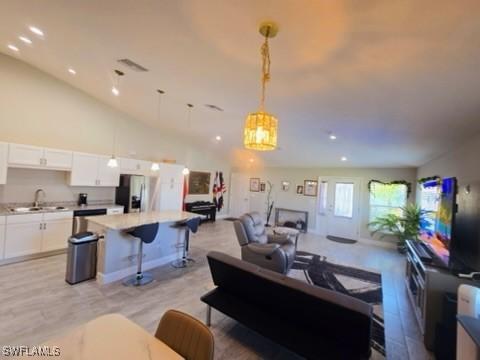 living room with light wood-type flooring, lofted ceiling, and sink