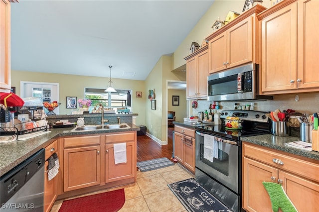 kitchen with light tile patterned flooring, appliances with stainless steel finishes, vaulted ceiling, and sink