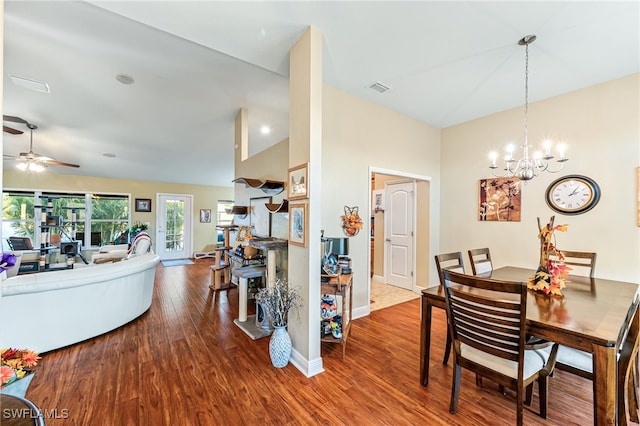 dining area with hardwood / wood-style floors, ceiling fan with notable chandelier, and lofted ceiling