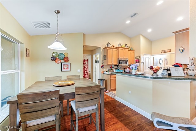 kitchen featuring kitchen peninsula, dark hardwood / wood-style flooring, decorative light fixtures, and vaulted ceiling