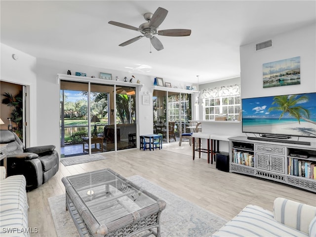 living room with plenty of natural light, ceiling fan, and light wood-type flooring