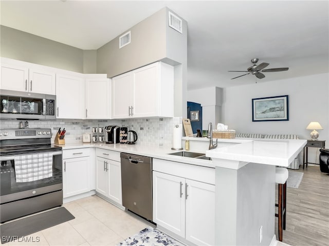 kitchen featuring sink, stainless steel appliances, a kitchen breakfast bar, kitchen peninsula, and white cabinets