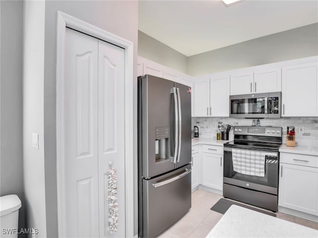 kitchen with white cabinets, light tile patterned floors, stainless steel appliances, and tasteful backsplash