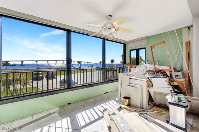 sunroom featuring ceiling fan, a water view, and french doors