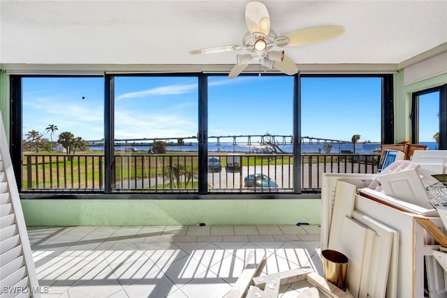 sunroom / solarium featuring ceiling fan and a water view