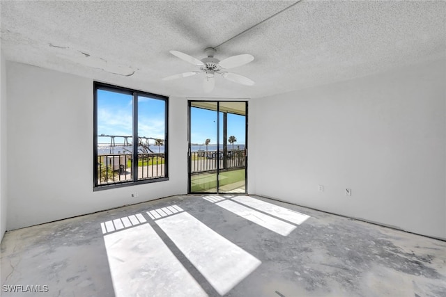 unfurnished room with a textured ceiling, ceiling fan, and concrete floors