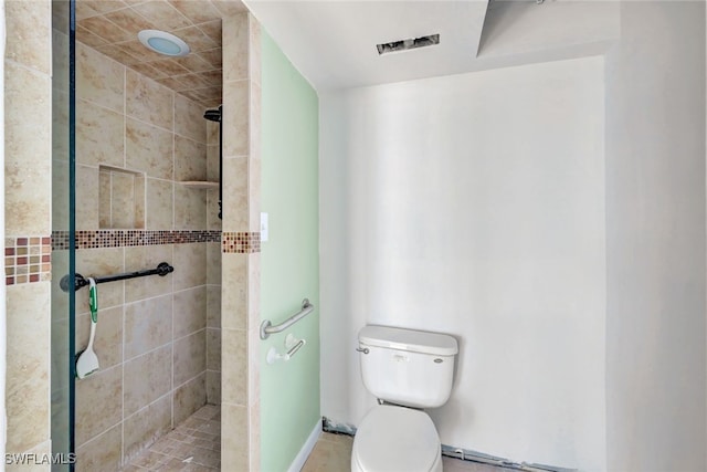 bathroom with a tile shower and toilet