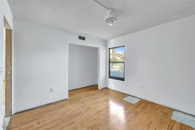 unfurnished room featuring light hardwood / wood-style floors and a textured ceiling