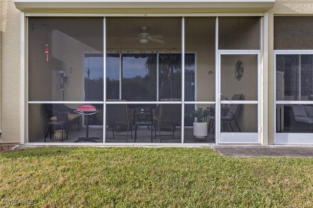 property entrance with ceiling fan and a lawn