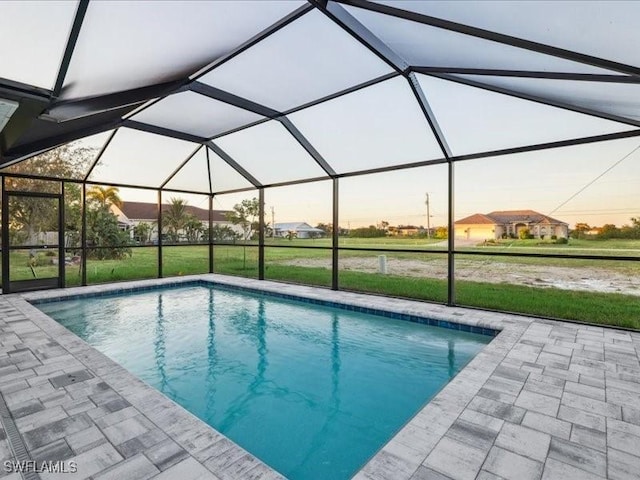 pool at dusk with a yard, a patio, and a lanai