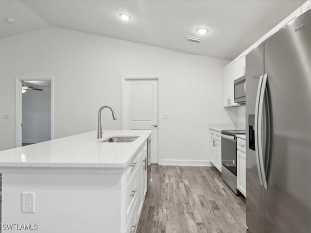 kitchen featuring a kitchen island with sink, sink, vaulted ceiling, white cabinetry, and stainless steel appliances