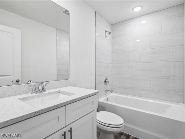 full bathroom featuring vanity, tiled shower / bath combo, and toilet