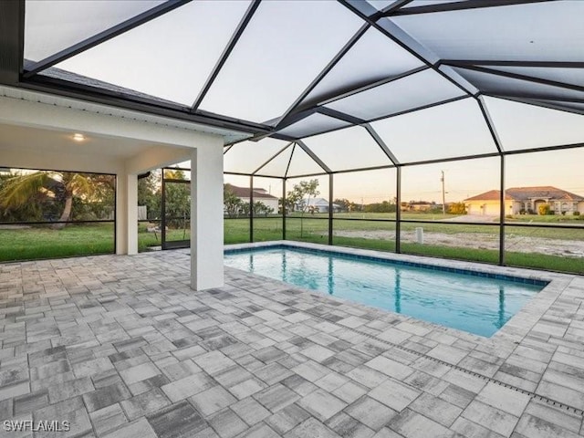 pool at dusk featuring glass enclosure and a patio area