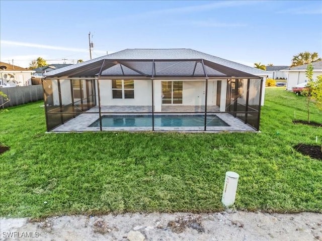 rear view of house featuring a fenced in pool, glass enclosure, a patio area, and a lawn