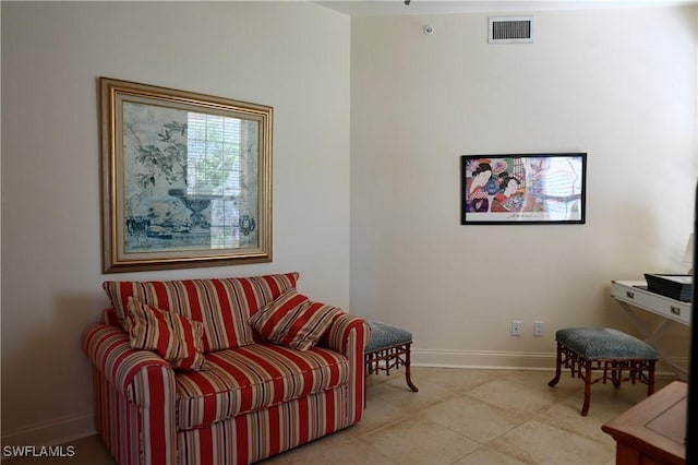 living area featuring light tile patterned floors, visible vents, and baseboards