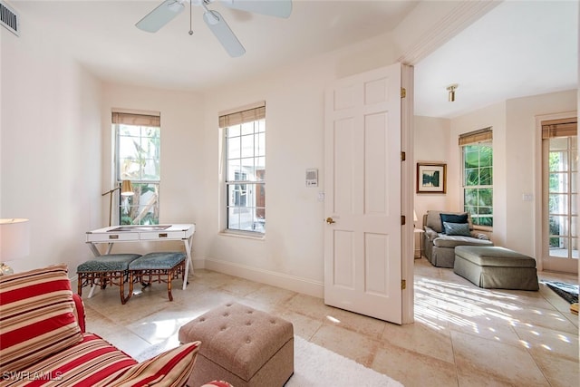 living area with tile patterned flooring, visible vents, ceiling fan, and baseboards