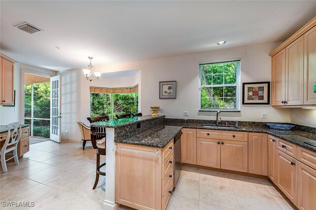 kitchen with light brown cabinets, a peninsula, a sink, visible vents, and dishwasher