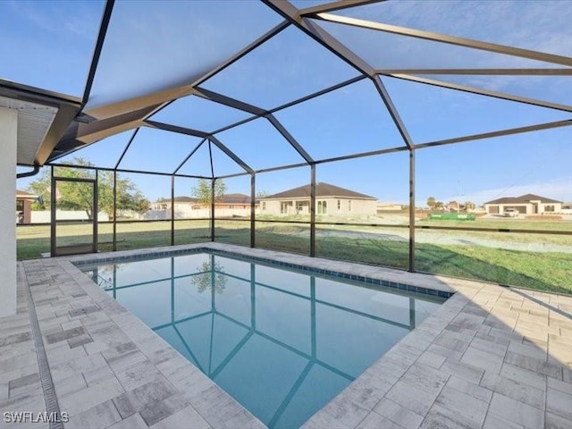 view of pool with a lawn, glass enclosure, and a patio area