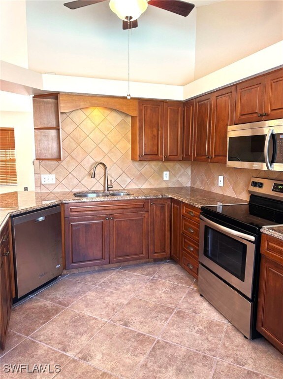 kitchen with decorative backsplash, light stone counters, sink, and appliances with stainless steel finishes