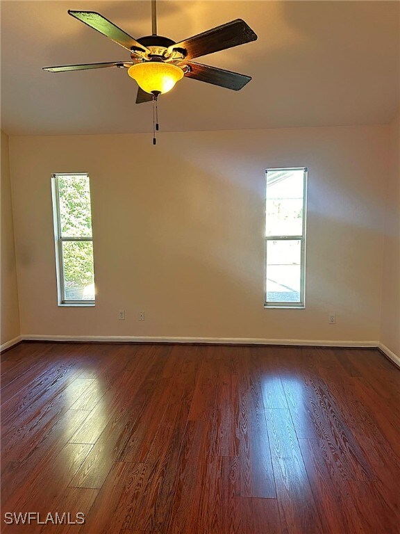 unfurnished room with dark wood-type flooring, ceiling fan, and a healthy amount of sunlight