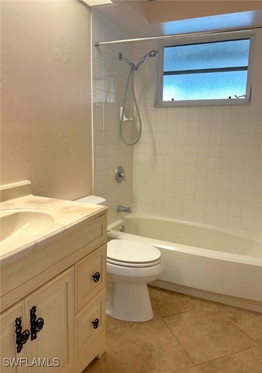 full bathroom featuring tile patterned floors, vanity, tiled shower / bath combo, and toilet