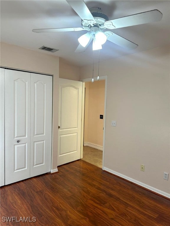 unfurnished bedroom featuring ceiling fan, dark hardwood / wood-style floors, and a closet