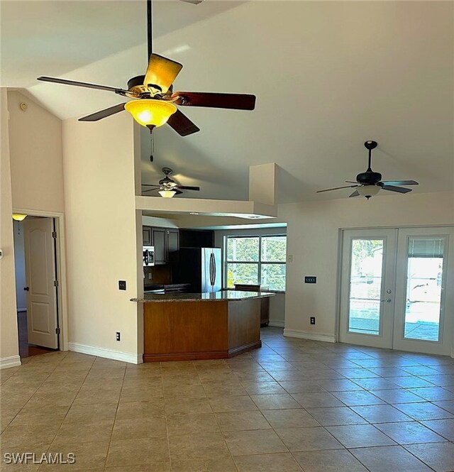 kitchen with stainless steel refrigerator, french doors, kitchen peninsula, lofted ceiling, and light tile patterned floors