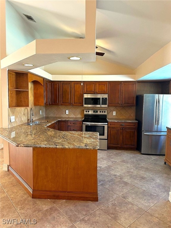 kitchen with vaulted ceiling, sink, light stone counters, kitchen peninsula, and stainless steel appliances