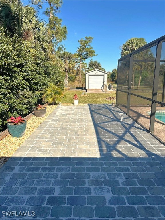 view of patio / terrace with a storage shed, a lanai, and a swimming pool